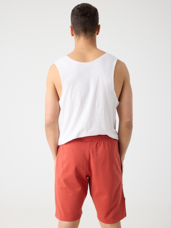 Bermuda jogger combinada com texto vermelho alaranjado vista meia traseira
