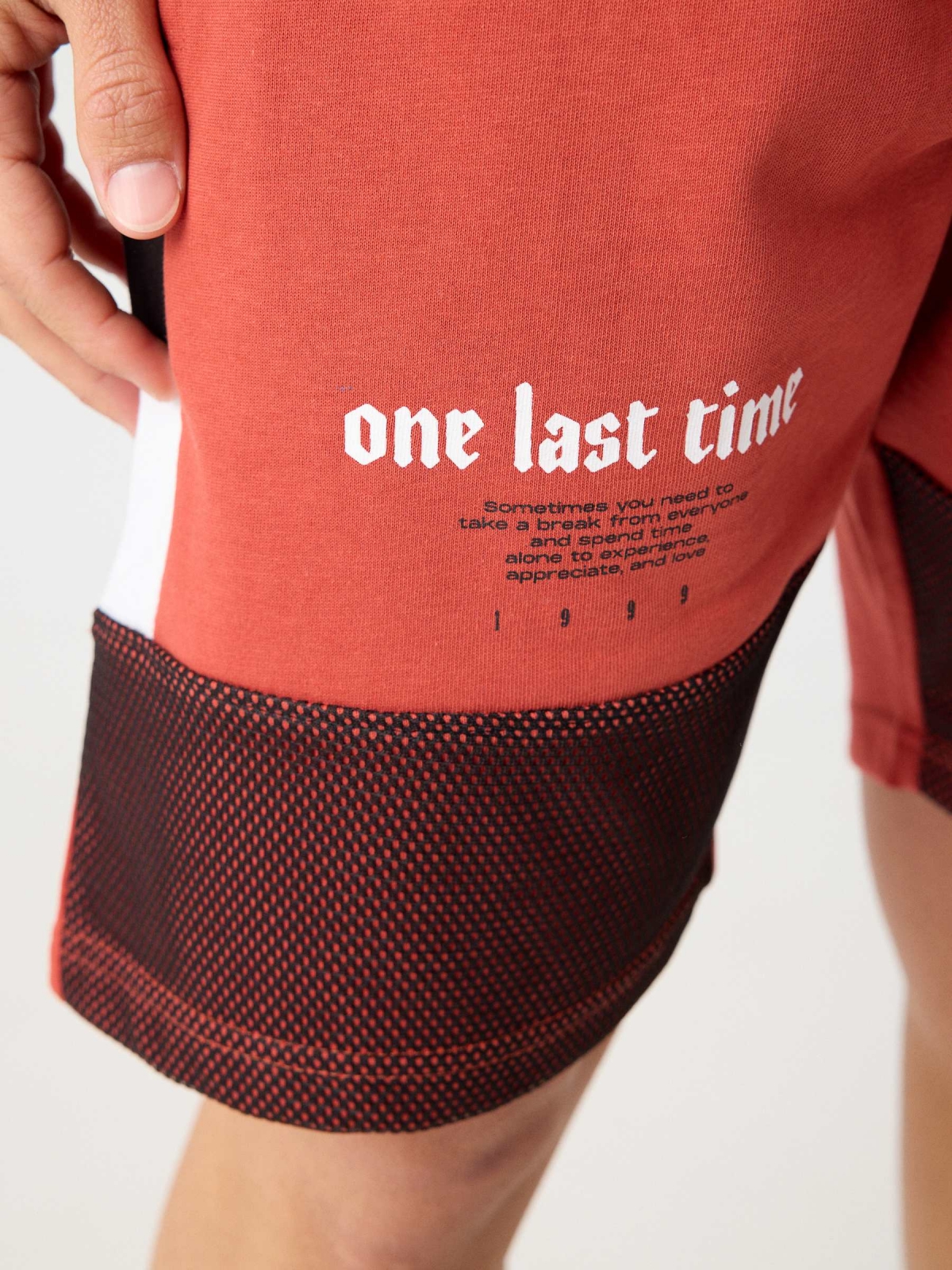 Combined bermuda jogger short with text orangish red detail view