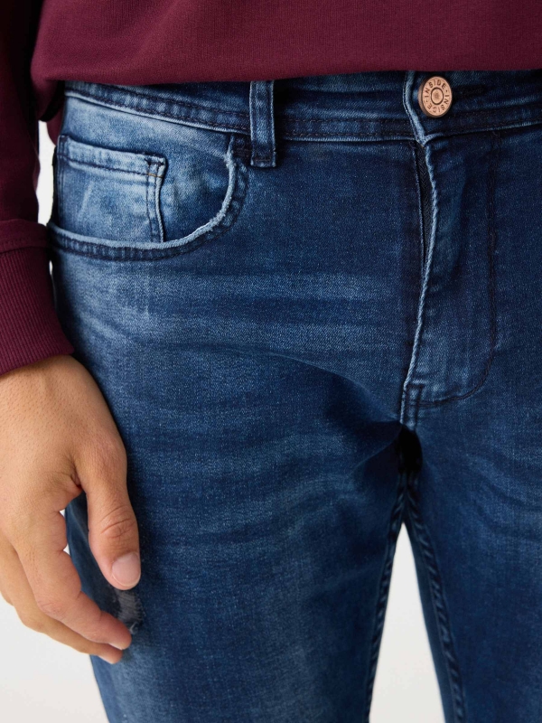 Jeans slim desgastado com rasgos azul marinho vista detalhe