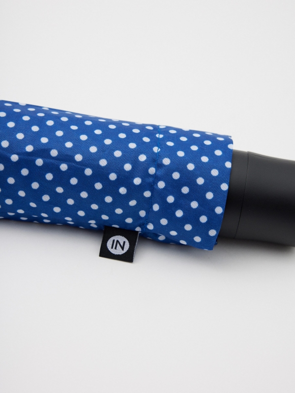 Polka dot folding umbrella blue foreground with a model