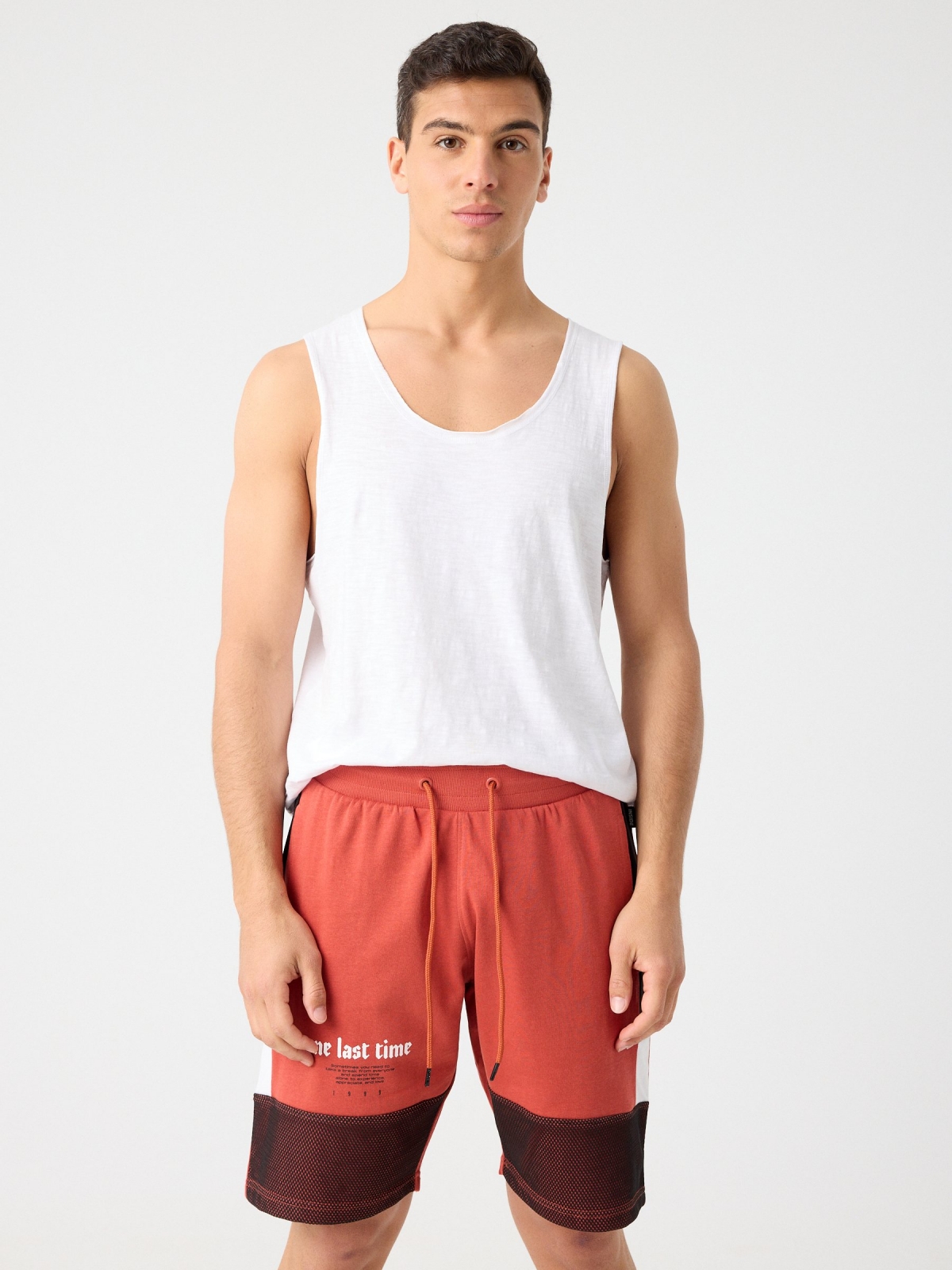 Bermuda jogger combinada com texto vermelho alaranjado vista meia frontal