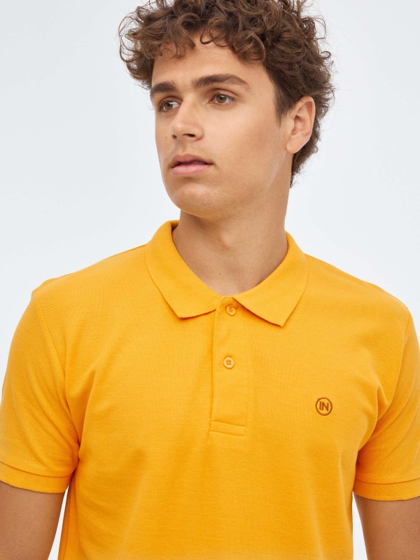 Polo básico logo grabado ocre vista detalle